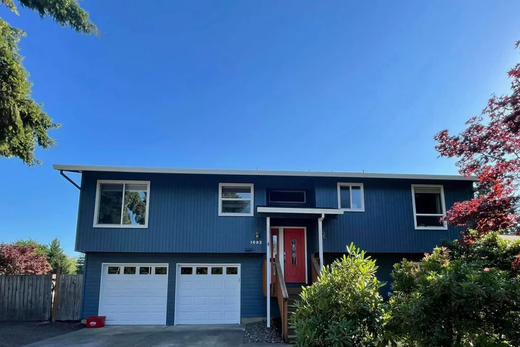 freshly-painted-blue-house-with-red-door-and-white-garage-doors