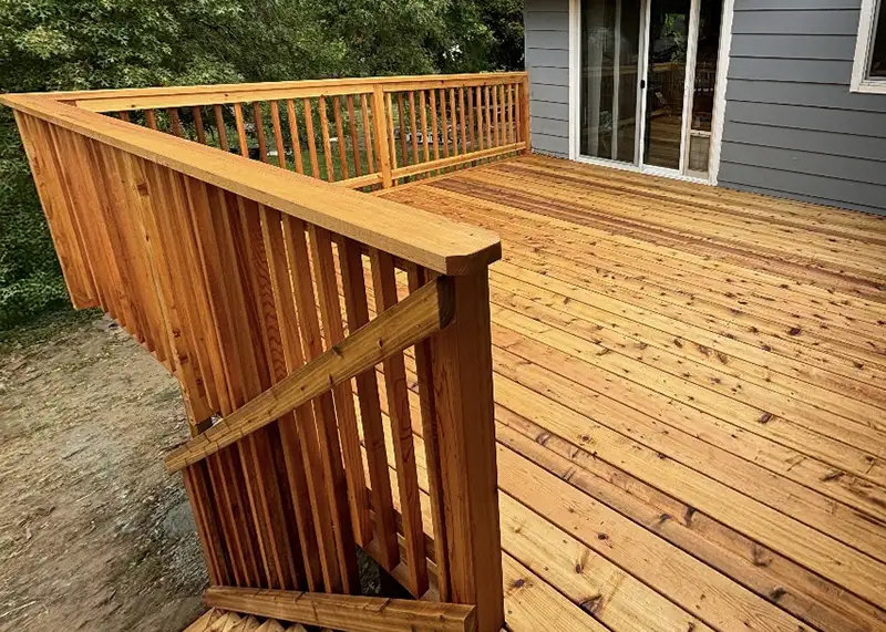Completed cedar deck with stairs, custom railing, and sliding door entry built by Salexx Construction