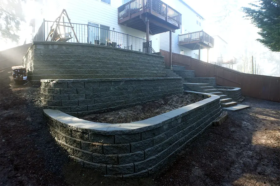 Backyard before outdoor living 3D design with retaining walls, stone steps, gravel areas, and raised garden beds in Newberg, Oregon