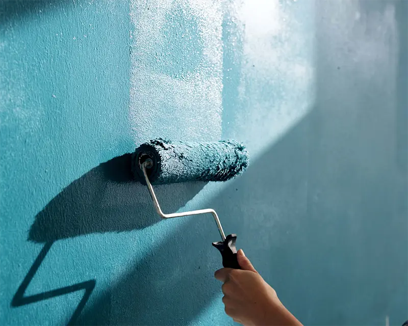 teal paint roller on commercial wall